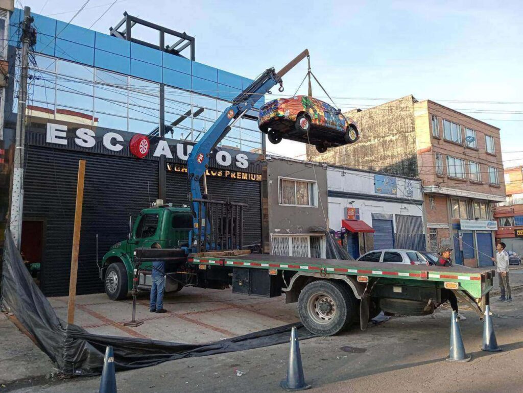 alquiler de camion grua en nemocon realizando maniobra de izaje de alta precision para instalacion de estructuras y vehiculos publicitarios.